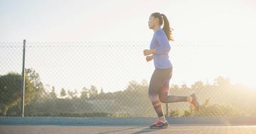 Female runner running past chain link fence